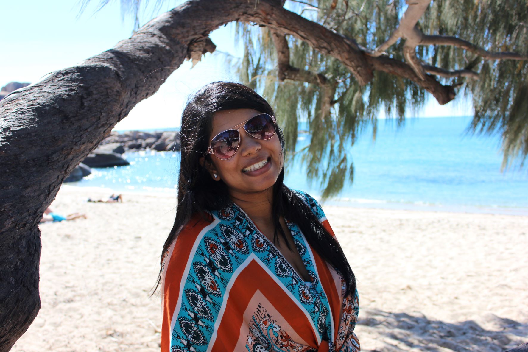 An image of a woman by the beach under a tree