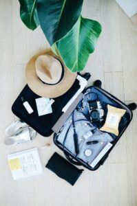 A suitcase containing travel items such as camera, hat, slippers, book, pen, wallet, pouch