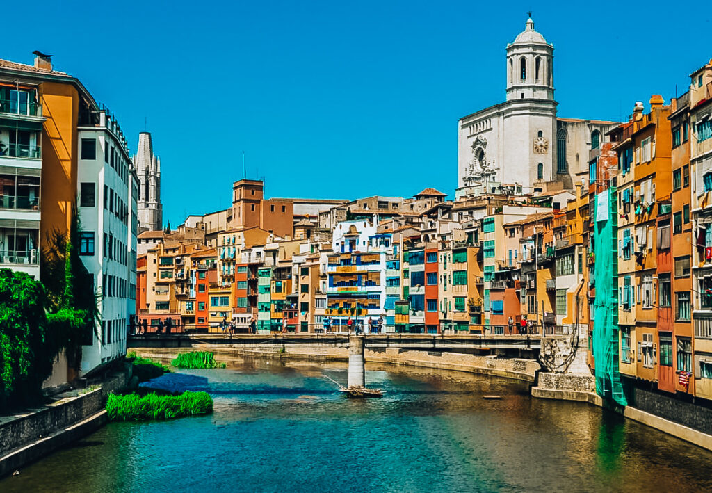 Colorful buildings of Girona lining the river with a concrete bridge running across it