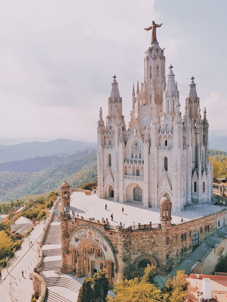 Mount Tibidabo and Sagrat Cor sitting on top of a hill with the mountains in the background