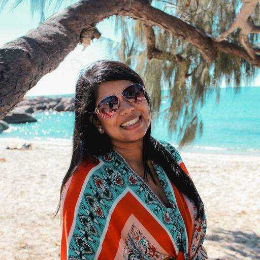 A photo of a woman in a shaded area of a beach under a tree