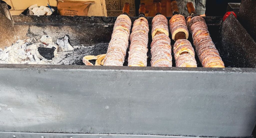 A coal spit with Trdelník, which is a rolled dough that is wrapped around a stick being grilled before its finished off with a sugar and cinnamon dusting