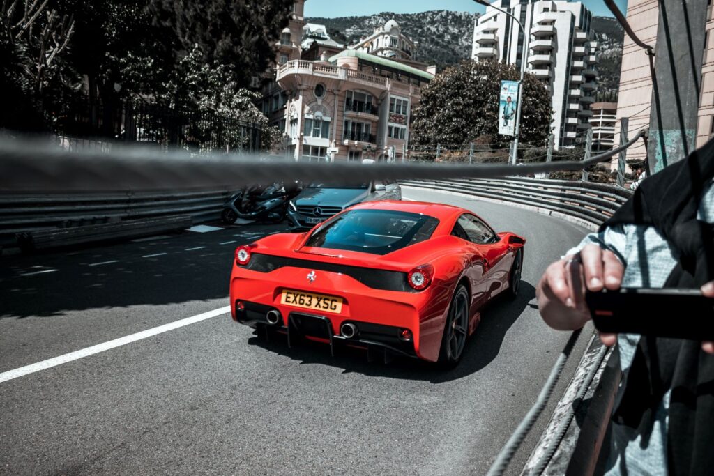 a red ferrari racing through the streets of Monaco with buildings on either side