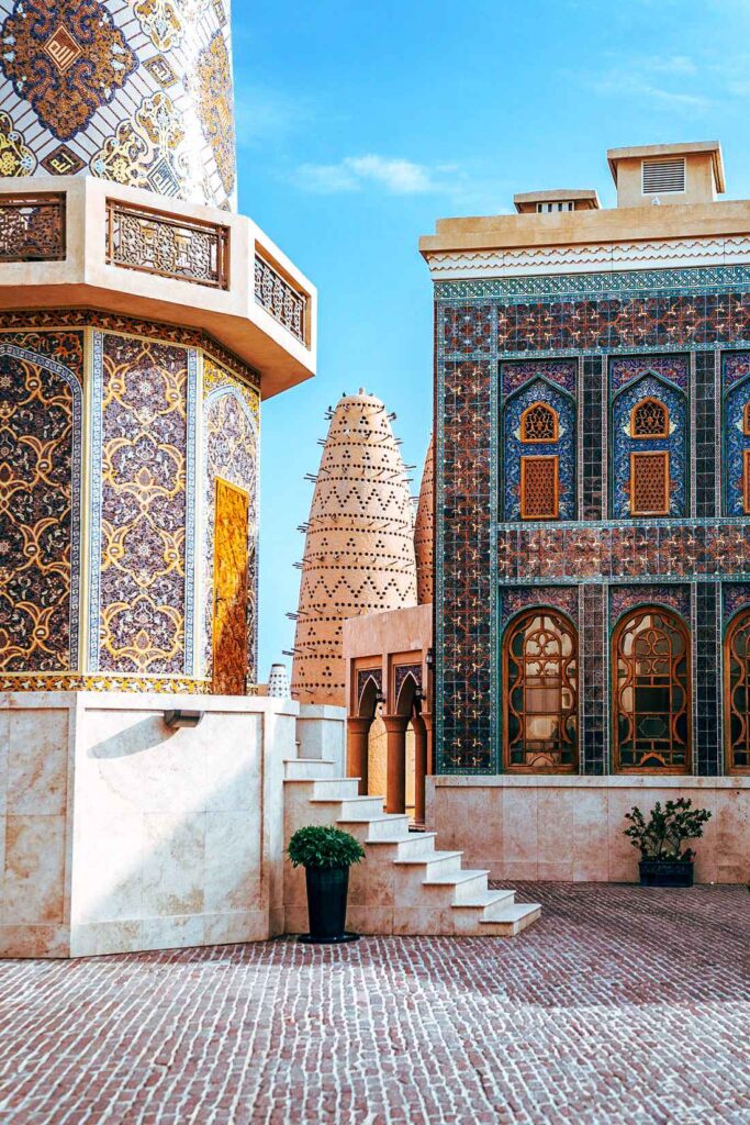 Blue, yellow,orange tield buildings sitting on brown concrete flooring with a white staircase leading up to one of the buildings