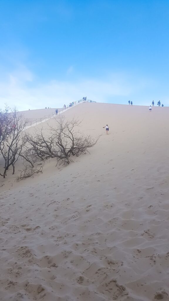 white sandy mountain with stairs leading to the top and people walking up the stairs. One of the top places to visit in the south of france