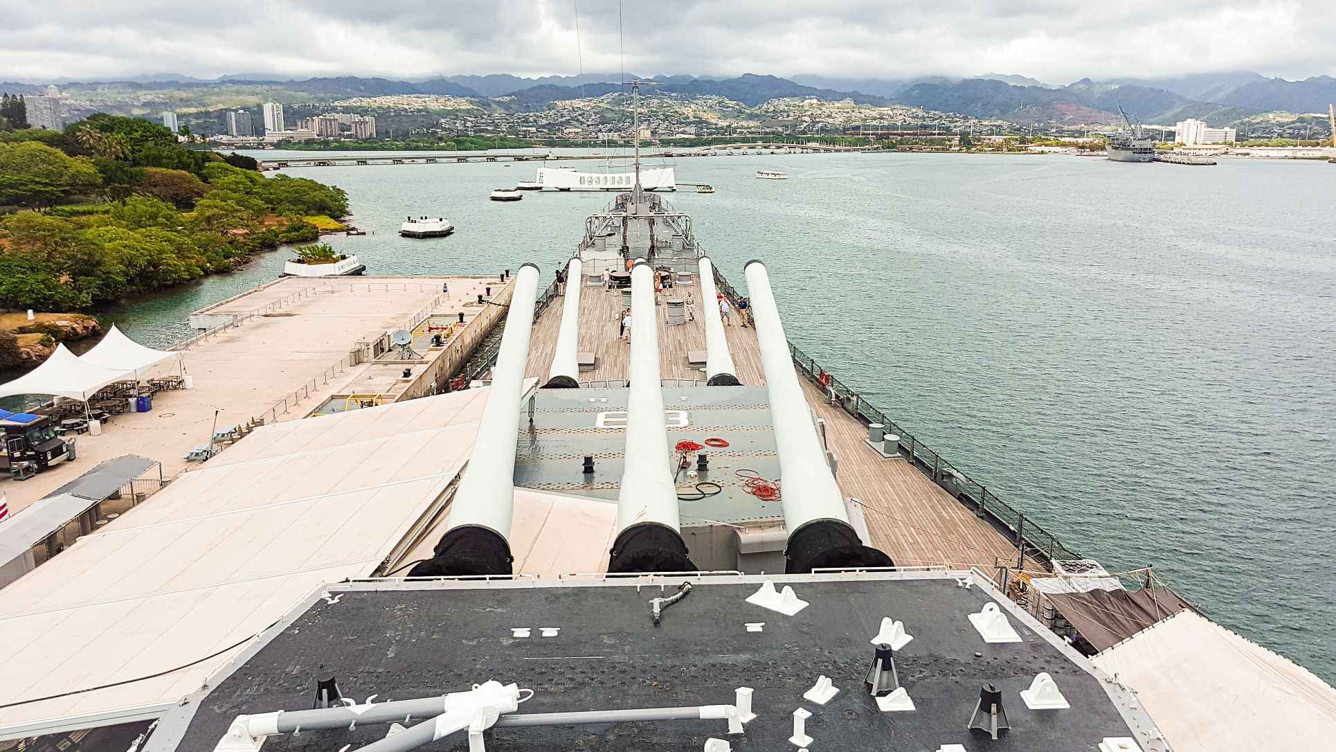 battleship looking out to white concrete structure sitting on a body of water during daytime