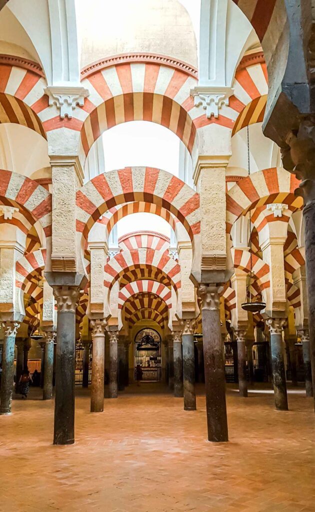 Concrete ground above which red and white arches lie. Definitely one of the highlights on the Southern Spain itinerary