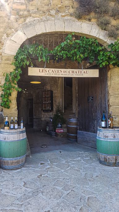 Arch entranceway with two green wine barrels at the entrance and green creepers hanging over the arch