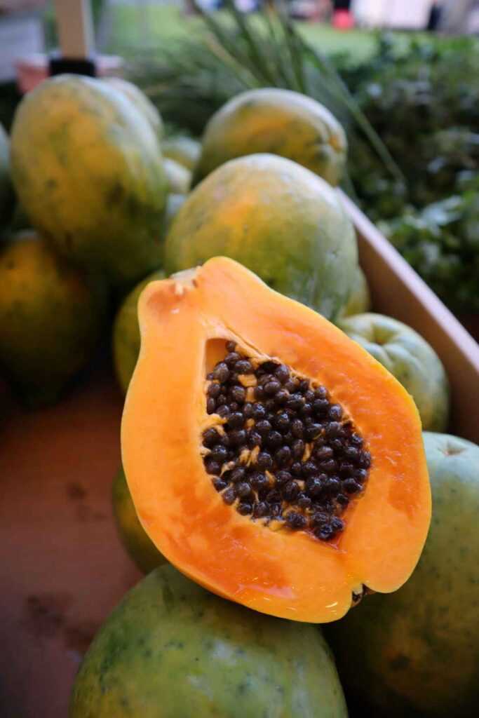 Cut fruit sitting on top of uncut fruits