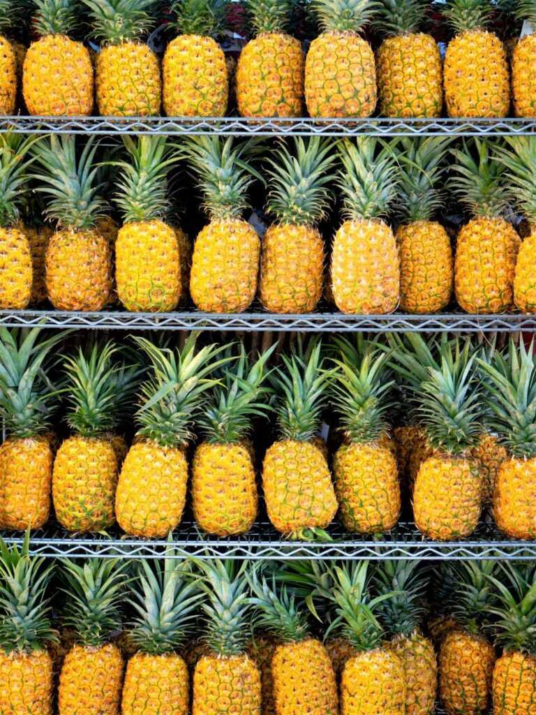 yellow and green pineapples sitting on a stand