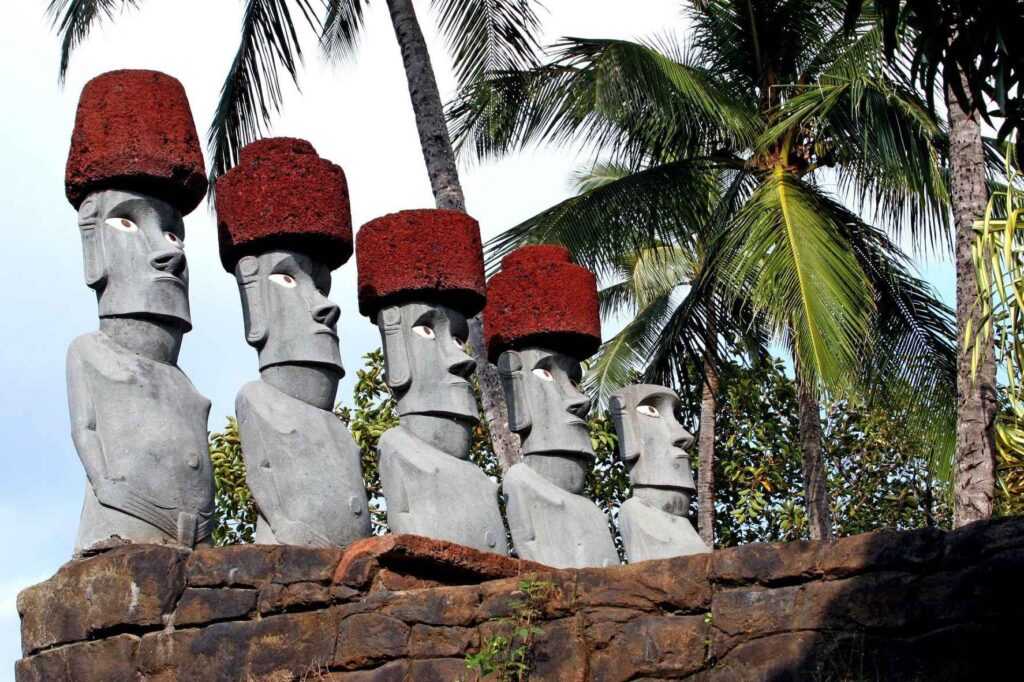 grey concrete statues with brown tops surrounded by green pal, trees