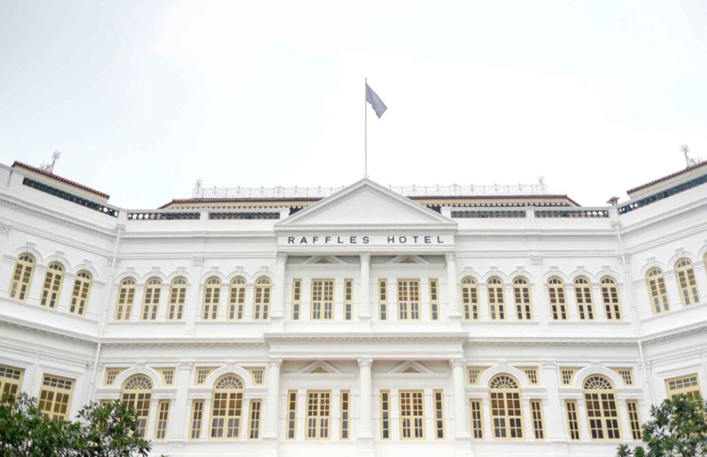 white colonial style building with flag flying up the top during day time