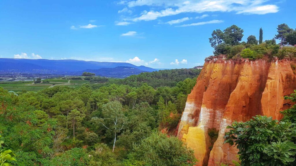 red and orange cliffs of Roussillin with green trees surrounding it