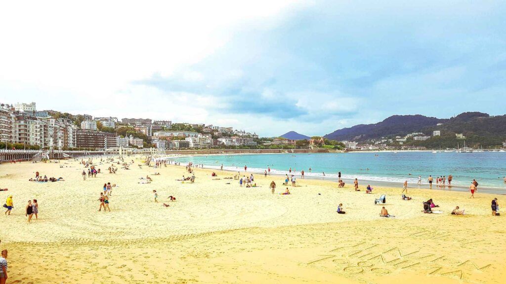 Golden sandy beach with turquoise blue water, people sunbathing and swimming on the beach