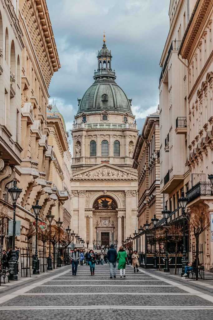 brown concrete building with green dome and people walking on the street during daytime