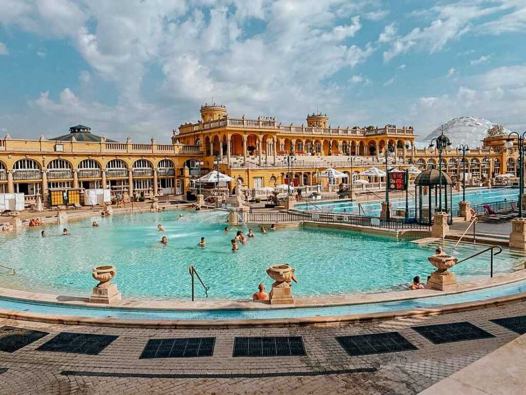 people in pools near yellow concrete building. One of the most popular things to do in Budapest.