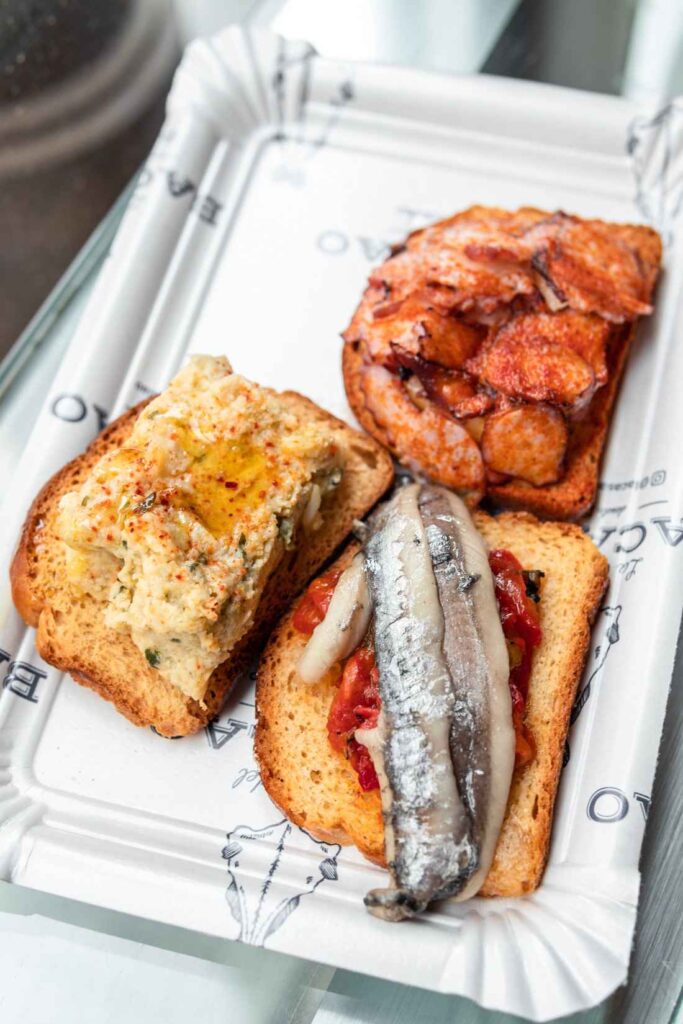 small bite sized meals consisting of bread, dips, anchovies and octopus