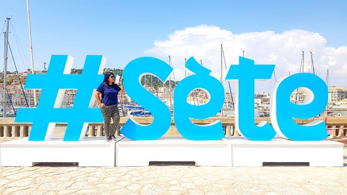 a large sign that reads sete with a girl standing near it