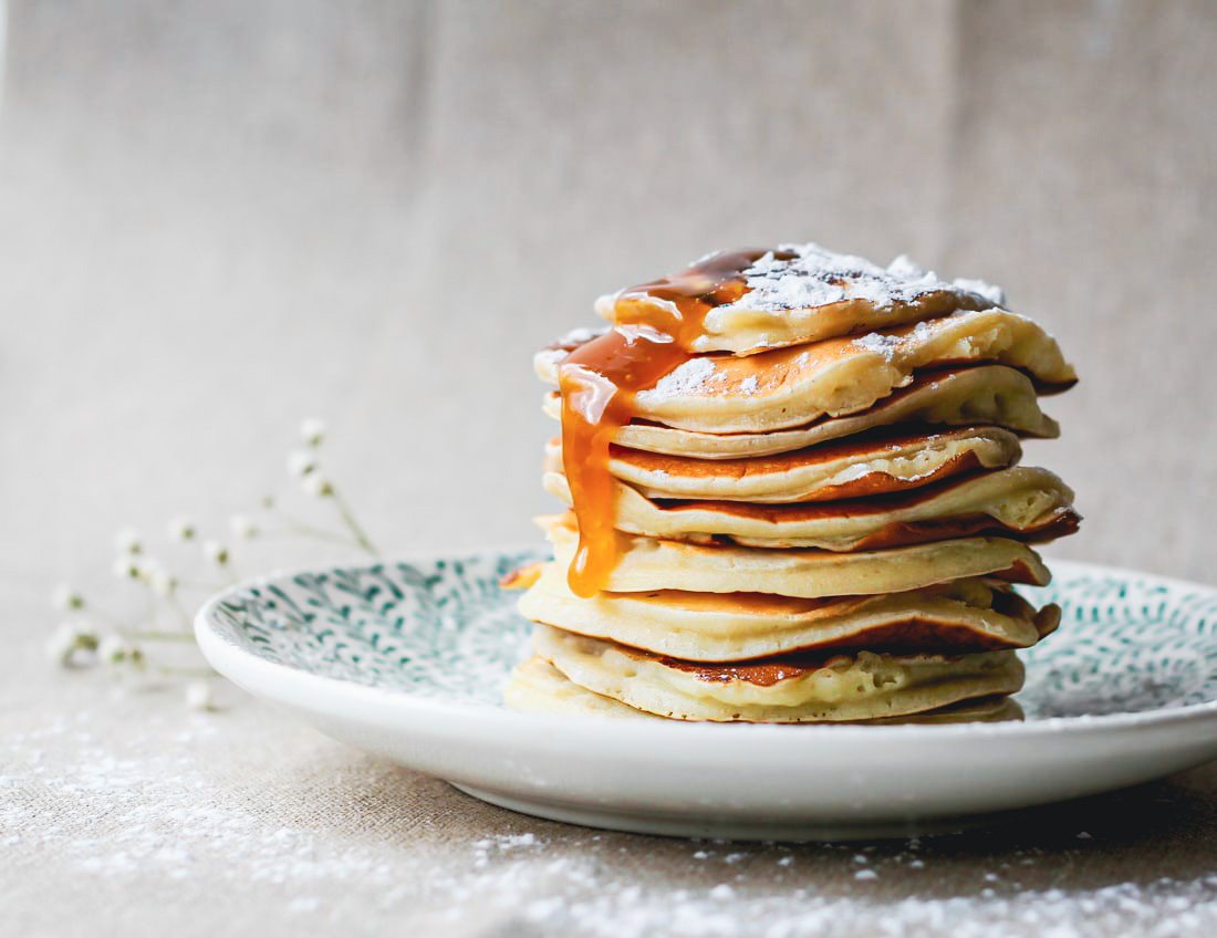 pancakes stacked on a plate with honey dripping on the side