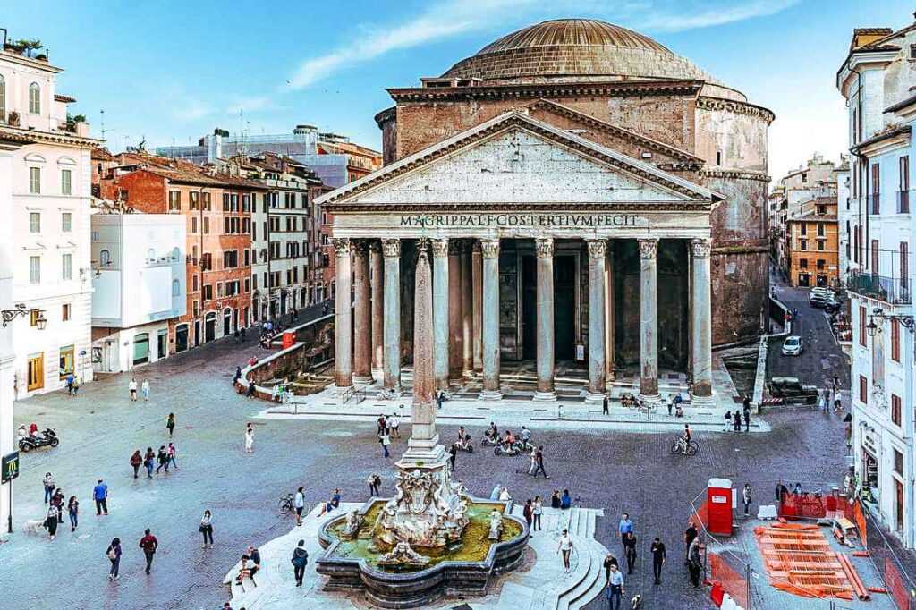 concrete structure during day time with people walking around in front of it. One of the best places to visit in Rome