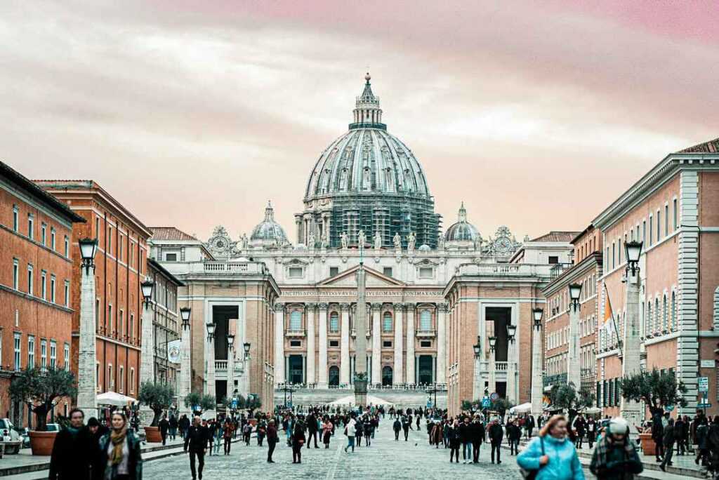 white concrete building with people walking around. One of the best places to visit in Rome