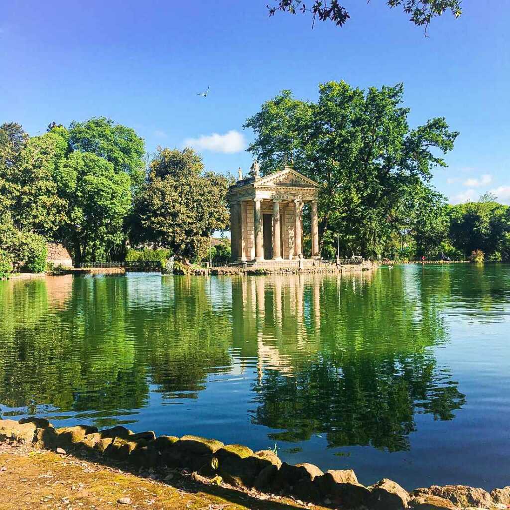 concrete structure in a body near a body of water and green trees during daytime