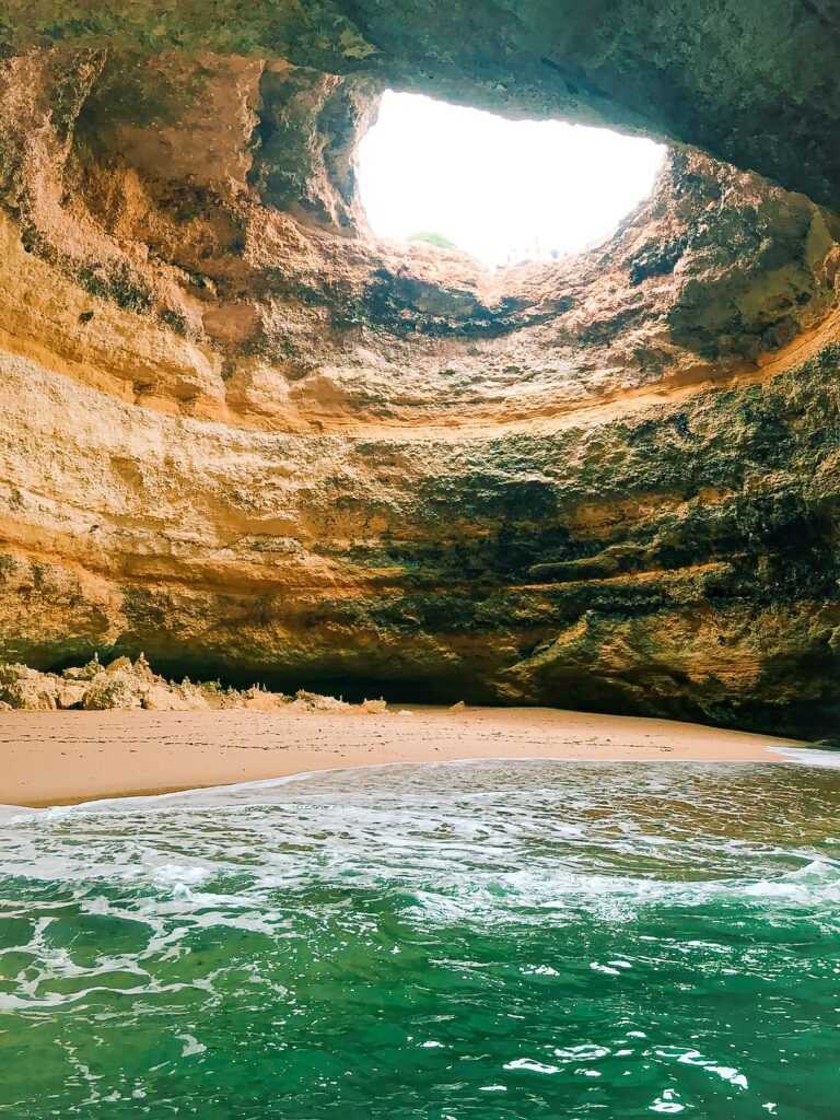 Limestone cave with hole in the ceiling and a body of water below. one of the best things to do during your two weeks in Portugal