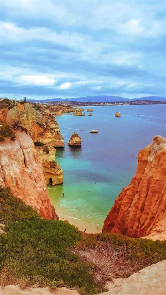 Beautiful limestone cliffs sitting by the edge of a calm water bed with boats in the water during daytime