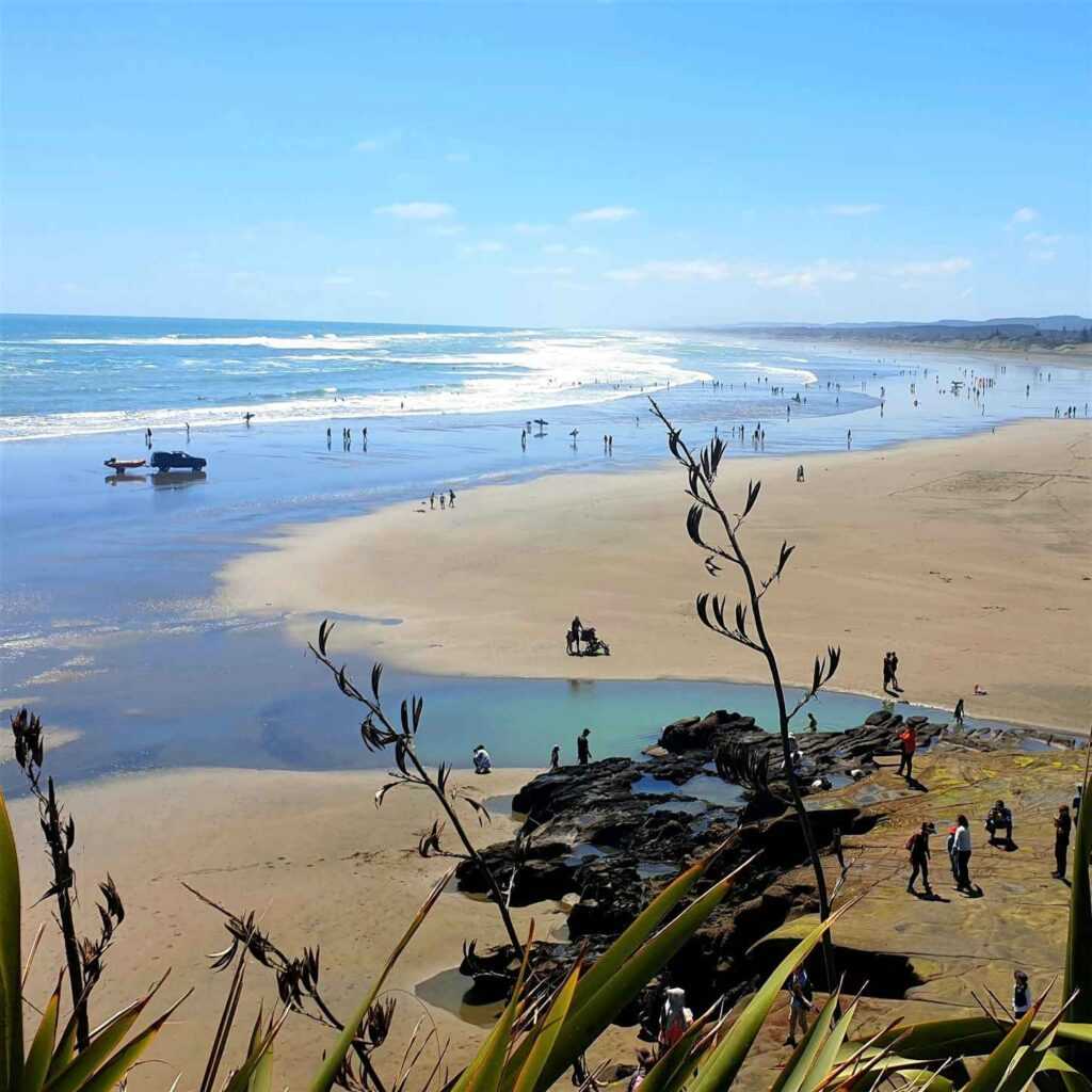 black sand beach during daytime with people walking on the beach