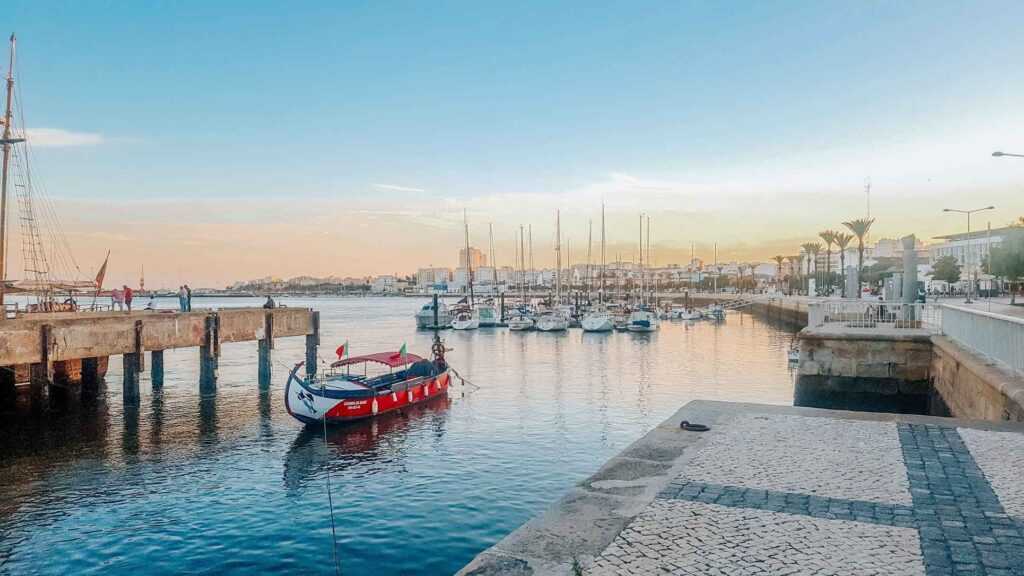 red boat sitting on the water at the wharf with boats in the background during sunset