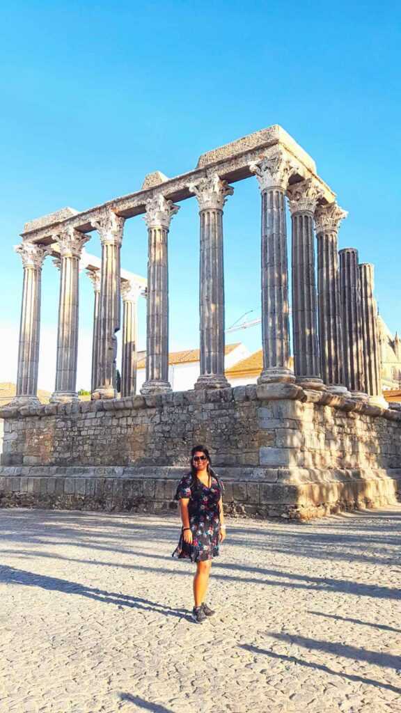 Girl standing infront of stone pillar structure during daytime