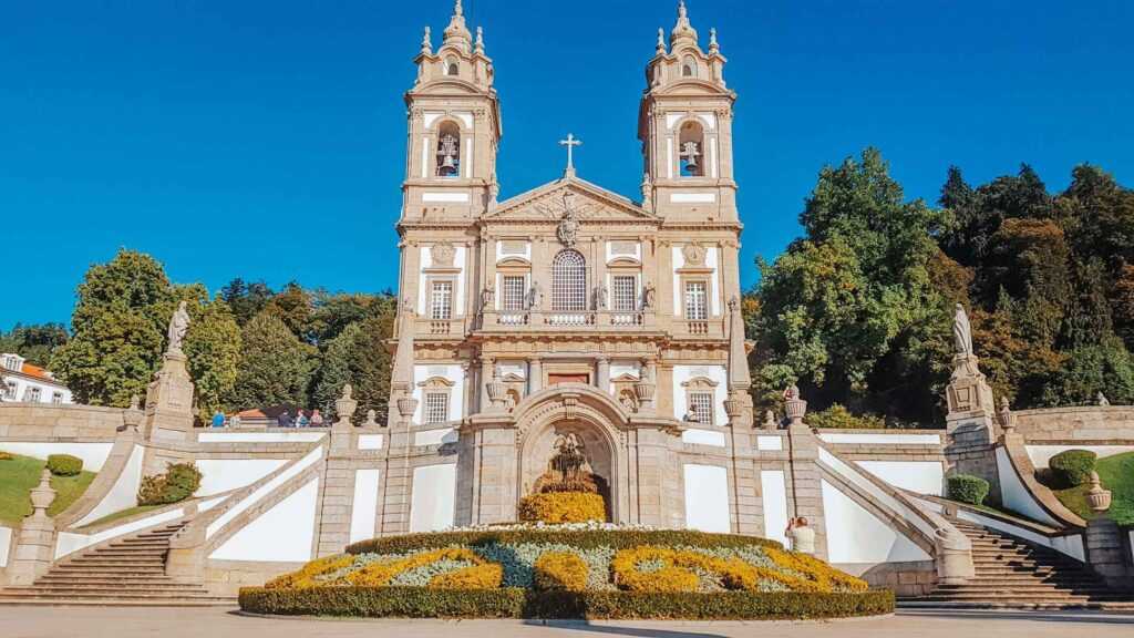 White church structure surrounded by a beautiful garden during daytime.  One of the most famous landmarks in Portugal