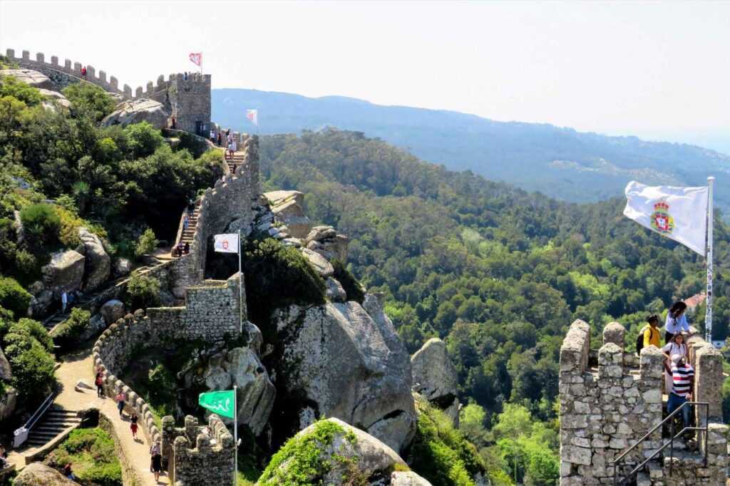 Stone wall and castle surrounded by trees during daytime