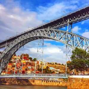 Steel Bridge over a body of water with colorful houses in the background during daytime