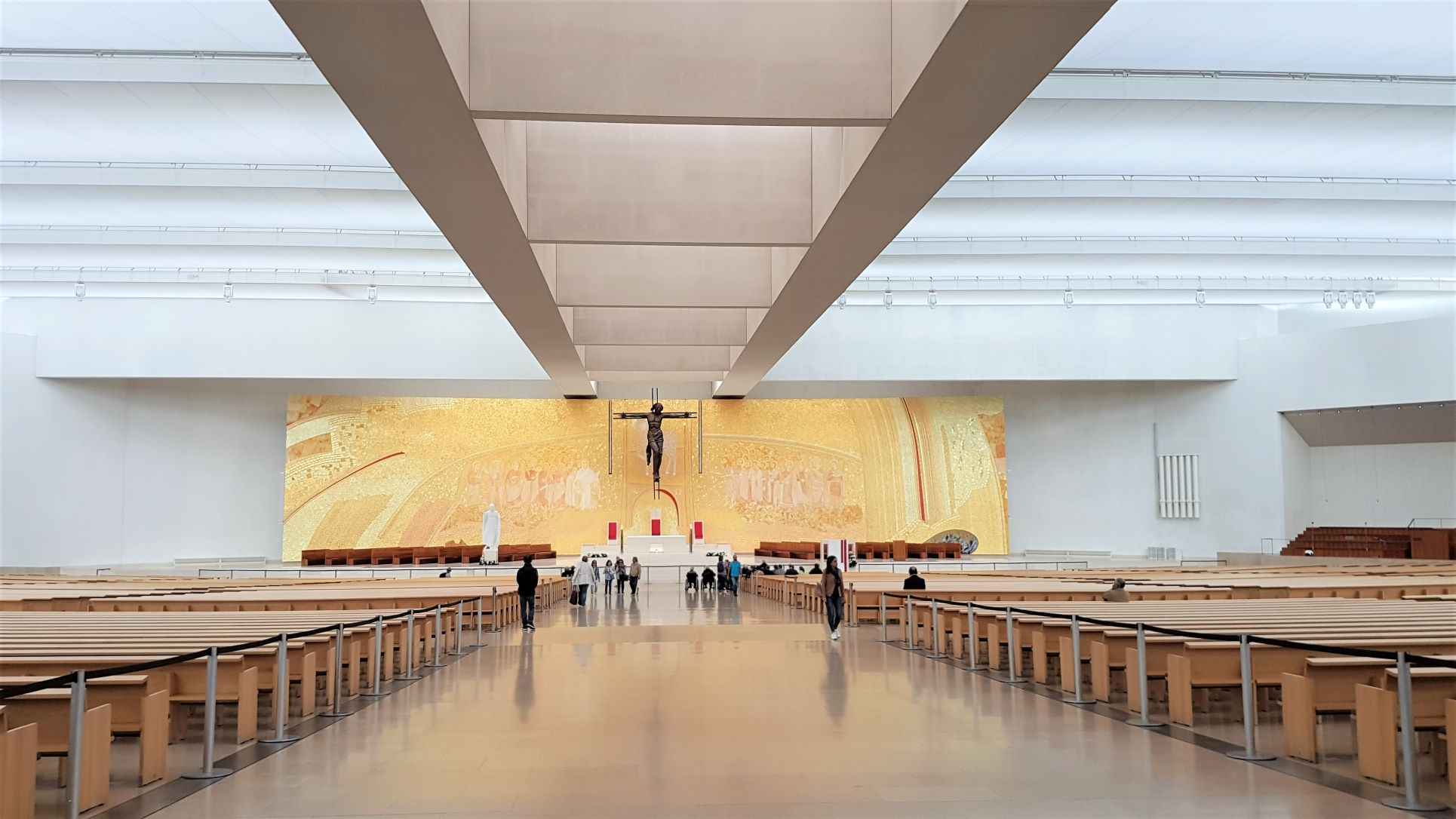 interior of a church with wooden benches and a gold altar