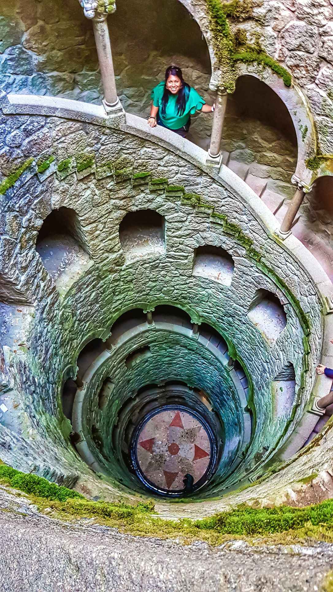 Spiral concrete well with woman standing looking up to the top. One of the most famous landmarks in Portugal