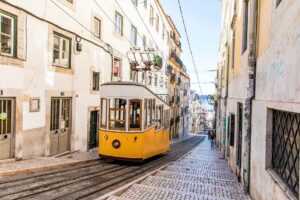 Yellow Tram moving upslope in between two buildings