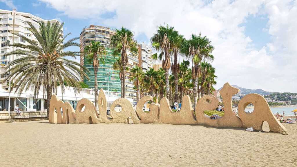 sand near palm trees and a large sand structure that spells Malagueta