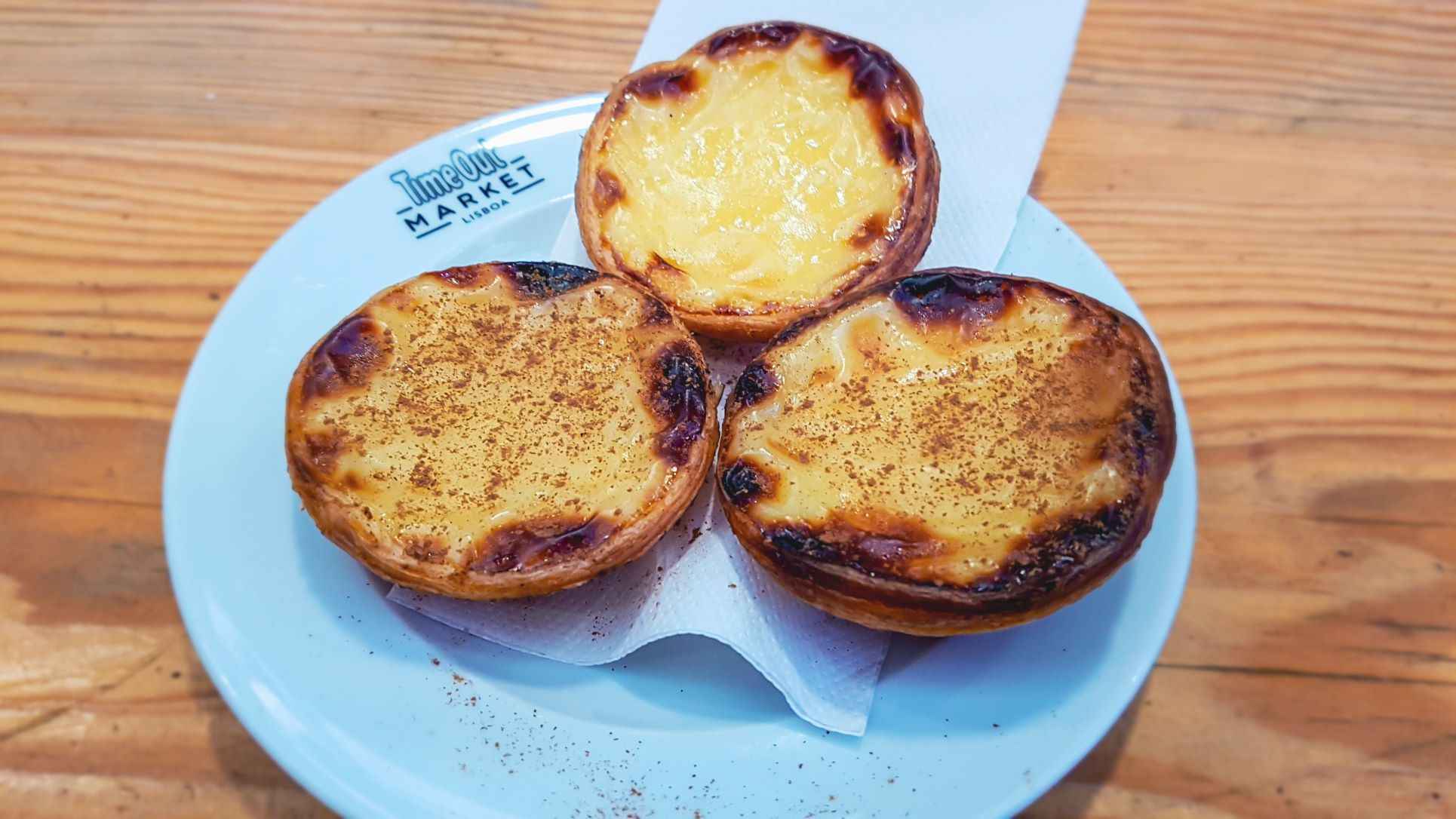 three puff pastry custard tarts on a white plate sprinkled with cinnamon