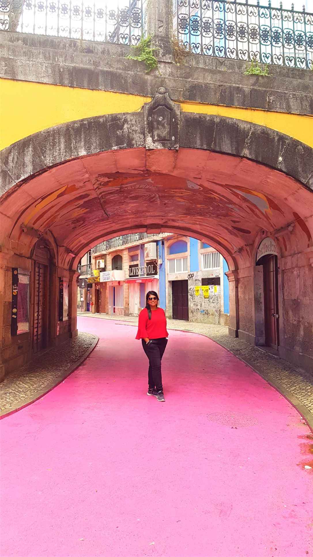 Girl standing on pink street under yellow bridge during daytime