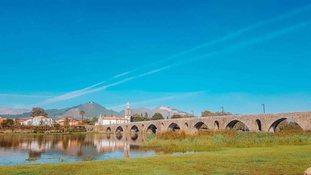 Concrete bridge sitting over body of water next to small white church during daytime