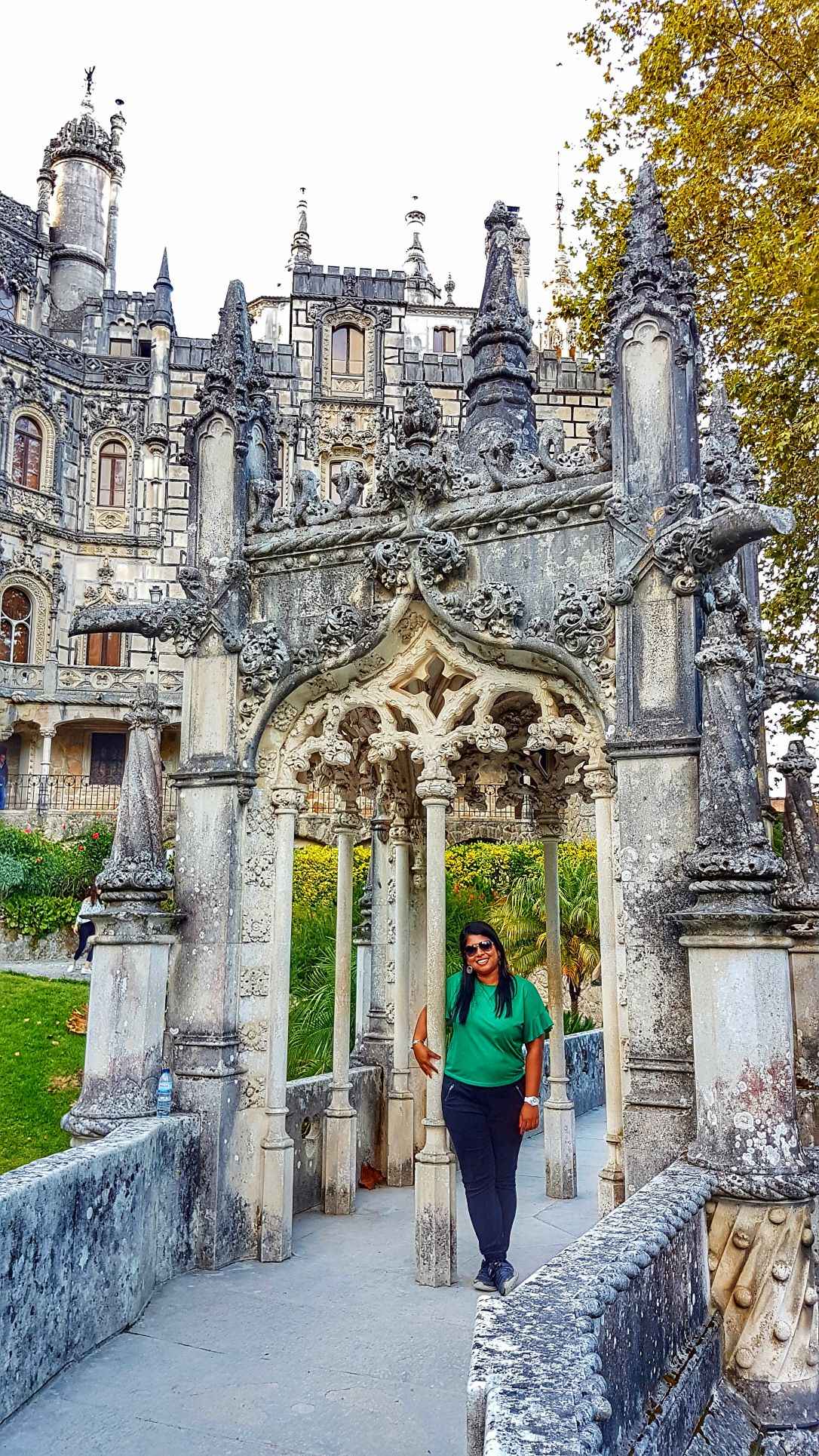 Grey concrete castle with archway and girl standing below it during daytime