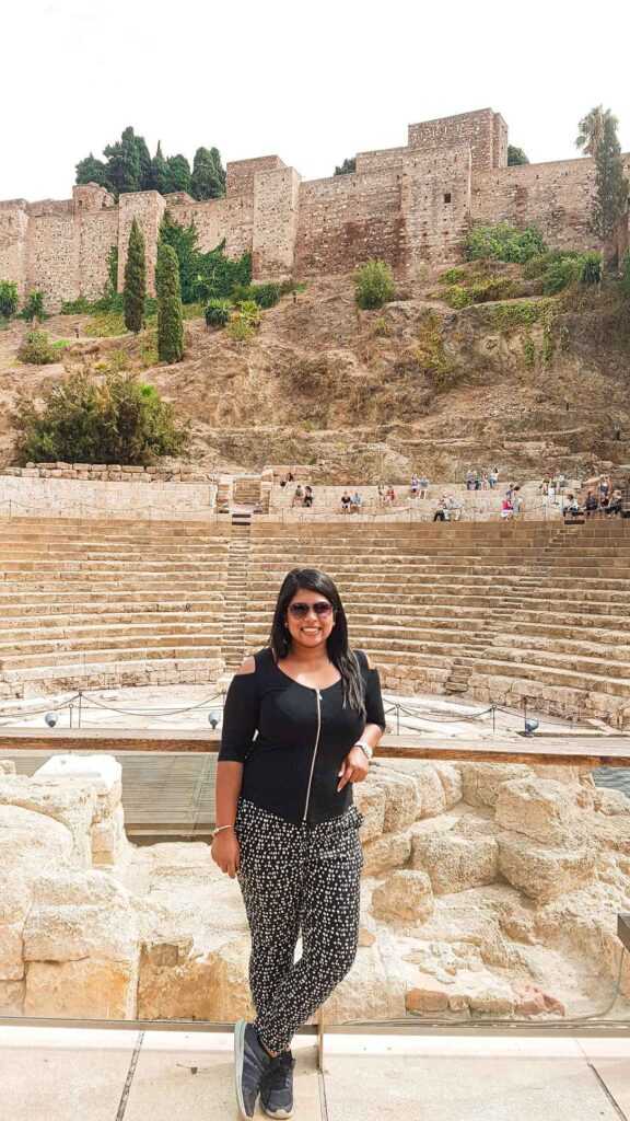 Girl standing in front of beige stone roman theatre during daytime