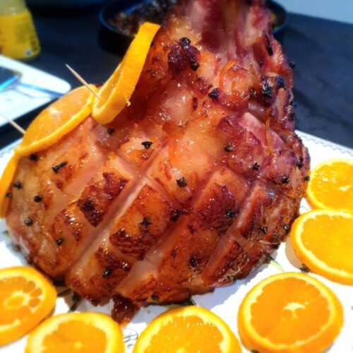 Piece of meat on the bone covered in orange slices