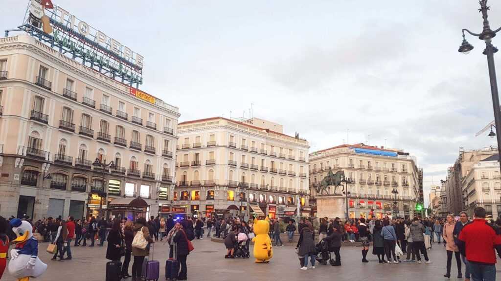 People walking in a plaza surrounded by concrete buildings during daytime