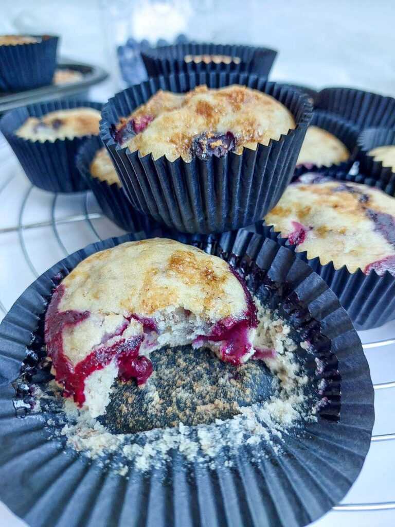 a bitten muffin amongst other muffins on a tray