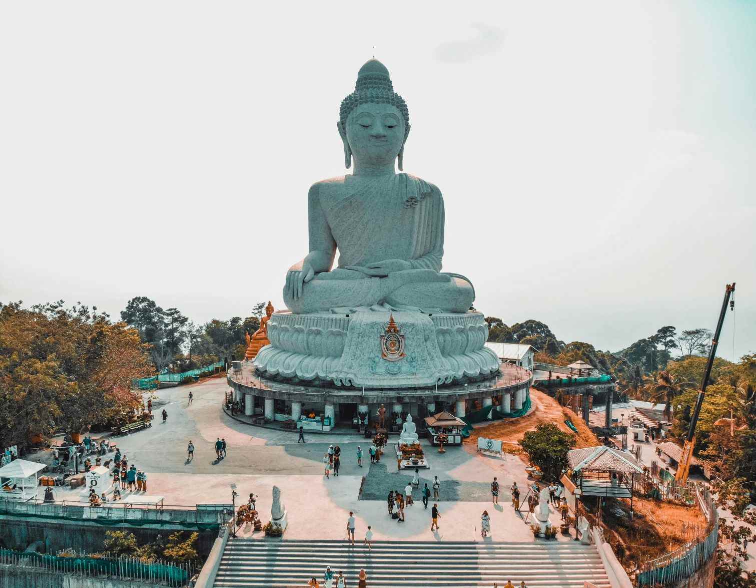 Massive white statue of Big Buddha sitting on top of a hill during day time