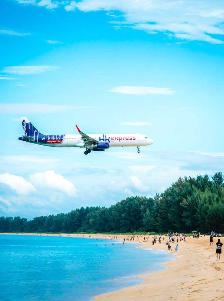 Aeroplane flying over a beach with people during daytime