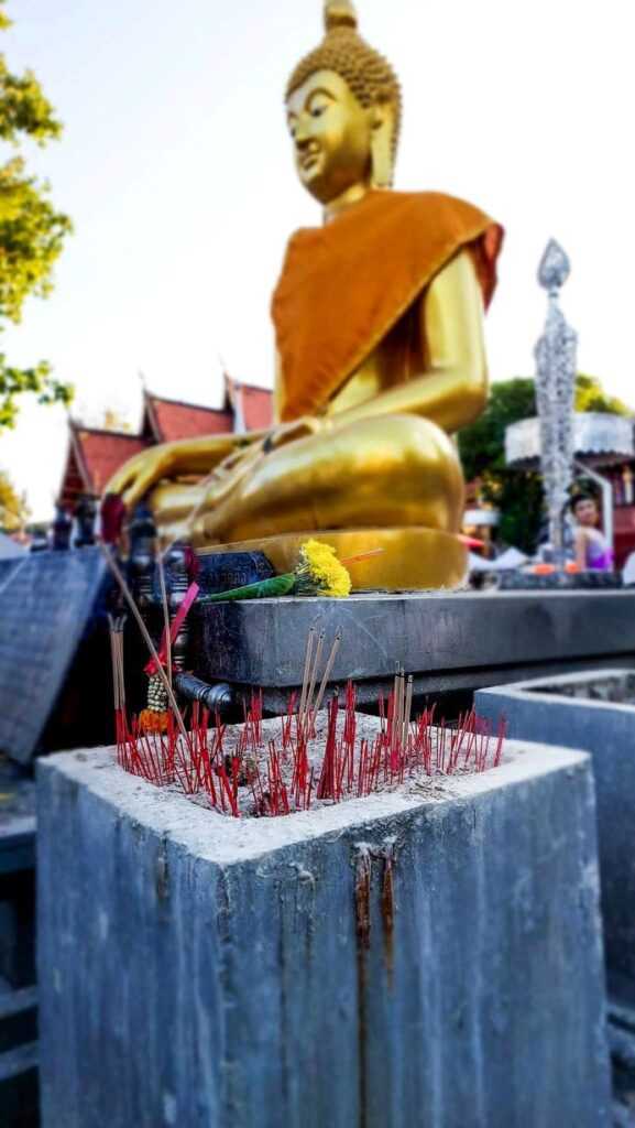 golden Buddha statue with incense sticks burning near it