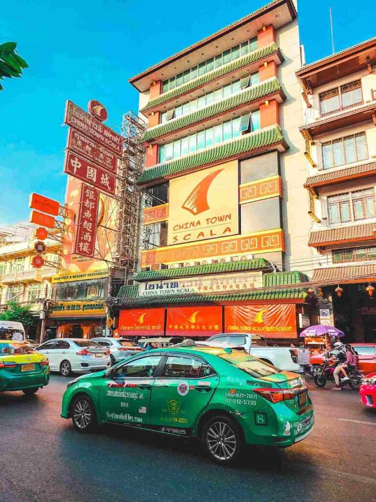 green car on a street infront of yellow and orange building during evening time